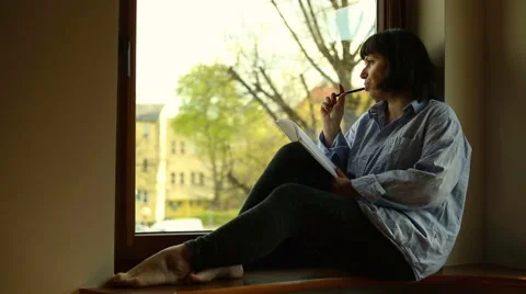 Woman write, sitting on windowsill Stock Footage 62825051
