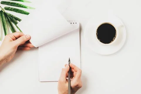 Woman writes makes notes by hand in blank notebook, a cup of coffee the desktop Stock Photos