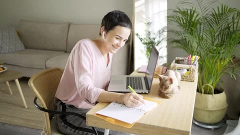 Woman writes in notebook at table with notebook and cat Stock-Footage 138789587