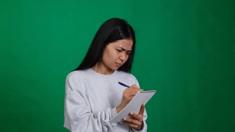 Woman writes on a notepad, jotting down ideas and plans. The scene includes a Stock Footage 279712078