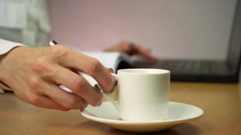 Woman writes notes while drinking coffee from a white cup. Video stock 241732884