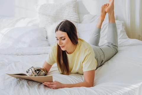 Woman writes in paper notebook with bionic arm lying on bed Stock Photos