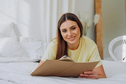 Woman writes in paper notebook with bionic arm lying on bed Stock Photos