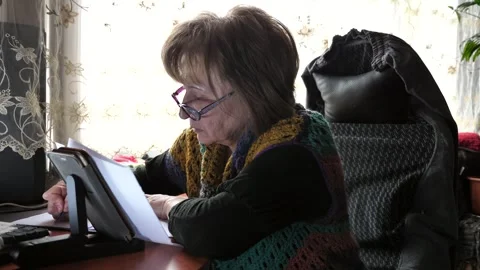 A woman writes with a pen in a notebook while sitting at a table. Stock Footage 332126155