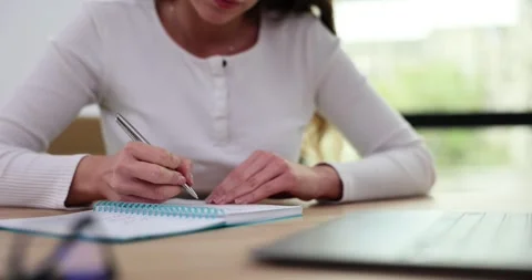 Woman writes text in paper notepad and laptop computer at workplace in office Stock Footage 256413312