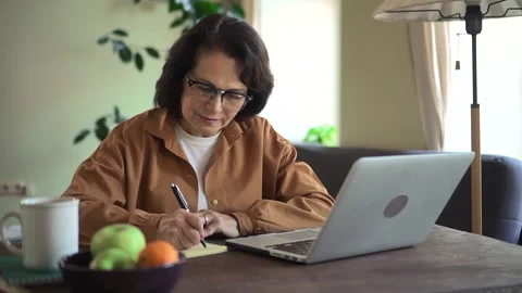 Woman writing and using computer during self education at table in apartment Video stock 152044929