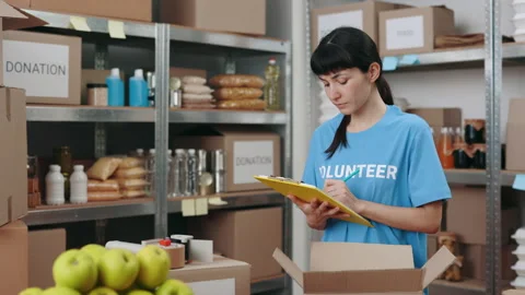 Woman writing on clipboard while checking donation storage Stock Footage 178479576