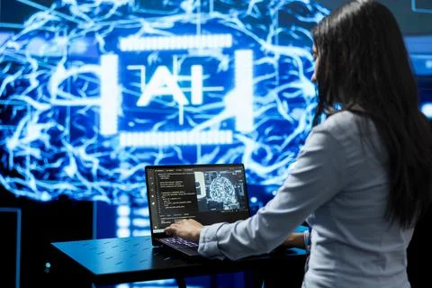 Woman writing code on laptop using AI model software Stock-Fotos