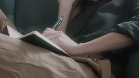 Woman writing down notes in her notebook while speaking on the phone Stock Footage 131055572