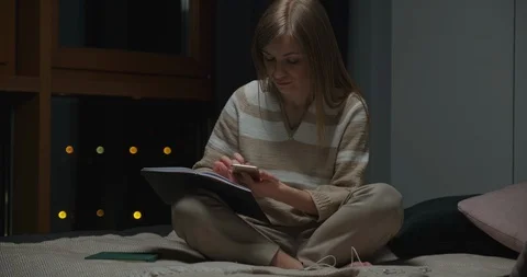 Woman writing in her note book in the night. She sitting on the bed. Dolly shot Stock Footage 127621602