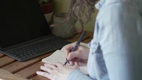 Woman writing in her notebook while working from home. Stock Footage 196823661