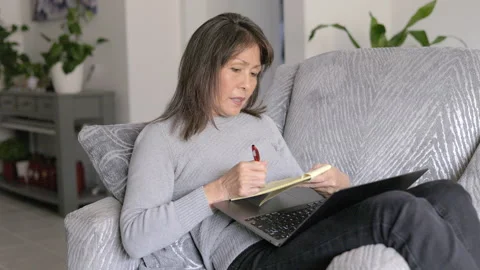 Woman writing message in note pad laptop computer on lap relaxing at home Stock Footage 325452471