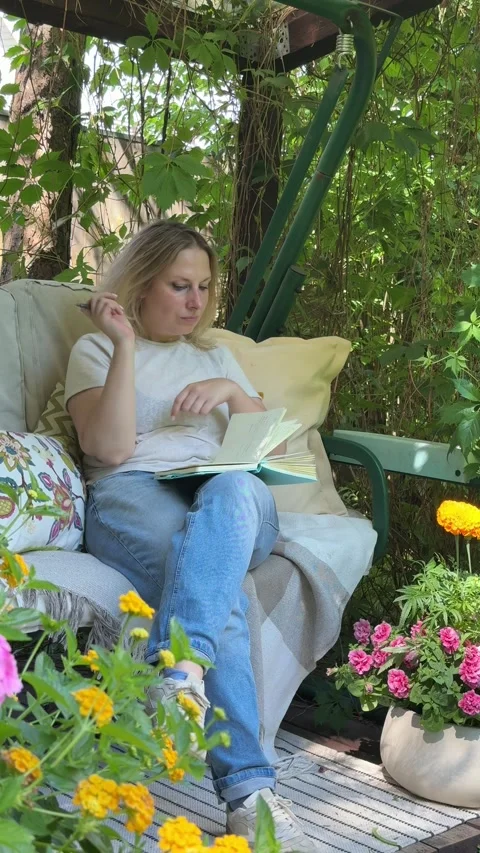Woman Writing in Notebook While Relaxing in Cozy Garden Retreat Stock Footage 337192421