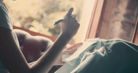A woman is writing in a notebook while sitting on a couch Stock Footage 284330703