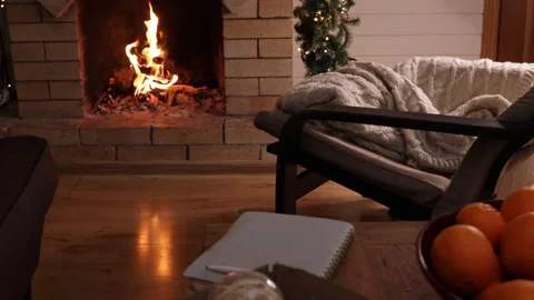 Woman writing in a notebook while sitting in an armchair by a burning fireplace. Stock Footage 326072289