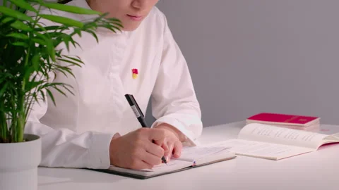 Woman Writing Notes in Notebook at Clean White Desk with Potted Plant Vídeos de archivo 334847629