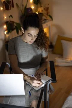 Woman writing notes in notebook working from home 库存照片