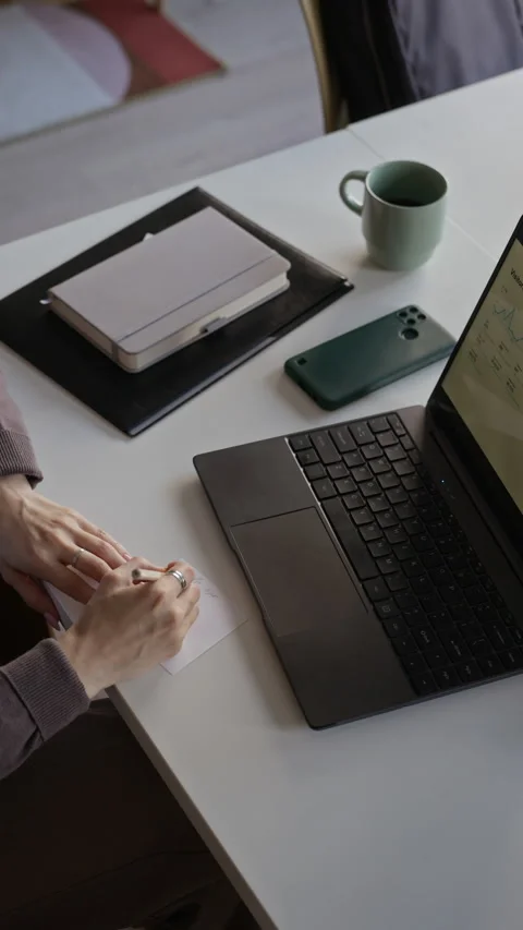 Woman Writing Notes While Analyzing Website Analytics on Laptop Stockbeeldmateriaal 347721705