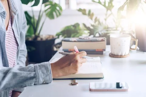 Woman is writing in planner notebook while using laptop to work or plan wit.. Stock Photos