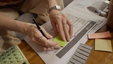 Woman Writing on Sticky Note and Managing Home Utility Bills Stock Footage 344647809