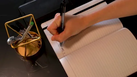 Woman writing task list on lined paper, note pad surrounded by office décor. Stock Footage 157818282