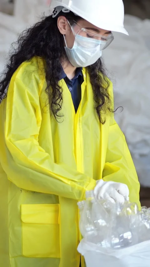 Woman In Yellow Coat Sorting Plastic Bottles For Recycling Reprocessing, Wearing Stock Footage 335522574
