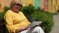 Woman in yellow jacket uses tablet computer.Woman holds Tablet-PC with earphones HD Footage