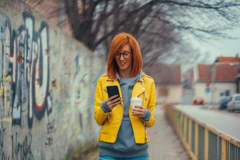 Woman in yellow jacket using smartphone Stock Photos