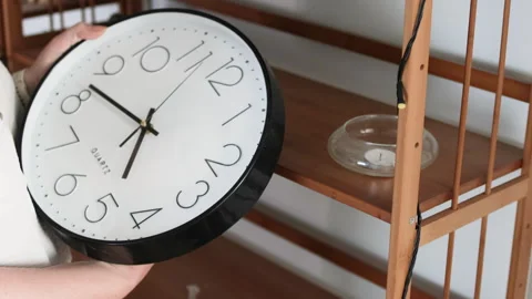 A womans arms adjust the hands of a wall clock. Stock Footage 310682592
