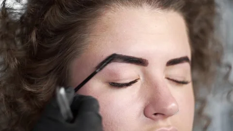Woman's brows been combed by eyebrow brush after coloring, eyebrow correction Stock Footage 90310076