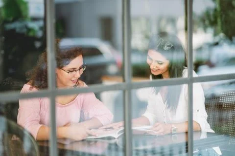 Womans chatting and reading while they sitting in a cafe Stock Photos