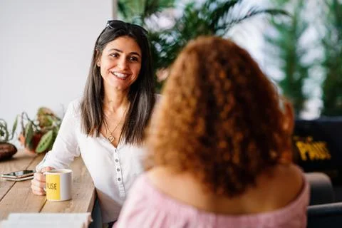 Womans chatting and smiling while they sitting and drinking some beverage in a Stock Photos