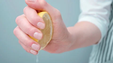 A woman's Chef hand squeezing lemon juice from a half lemon by hand in 4K. Stock Footage 140766636