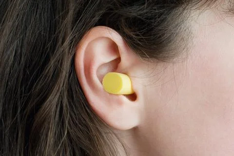 Woman's ear with an ear plug, noice  reduce, noice pollution . Stock Photos