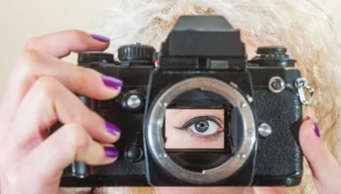 Womans eye looking through the open mirror box of a vintage 35mm film camera Stock Photos