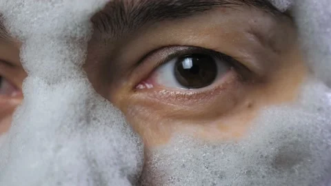 A woman's face with a gray bubble clay mask in a close-up. A girl applies a Stock Footage 232171449