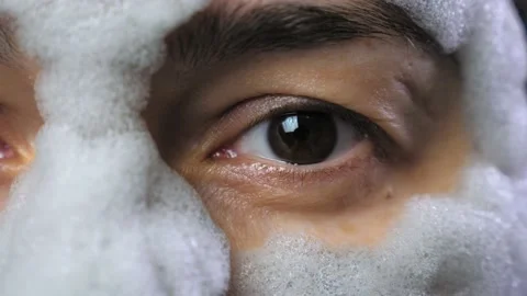 A woman's face with a gray bubble clay mask in a close-up. A girl applies a Stock Footage 232423869