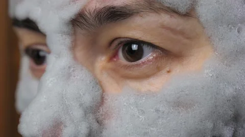 A woman's face with a gray bubble clay mask in a close-up. A girl applies a Stock Footage 233048403