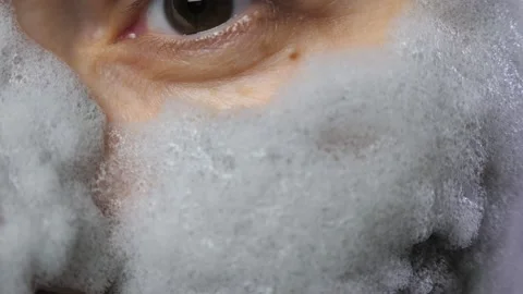 A woman's face with a gray bubble clay mask in a close-up. A girl applies a Stock Footage 233273294