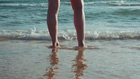 Woman's feet hit by a small wave on the seashore Stock Footage 201263663