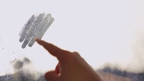 Woman's finger painted doodle shape for text on muddy glass wet window Stock Footage 258768010