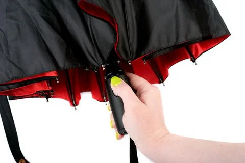 A woman's finger presses the button of an automatic umbrella. Photos