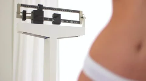 Woman's flat stomache after weight loss in front of scale Stock Footage 22340627