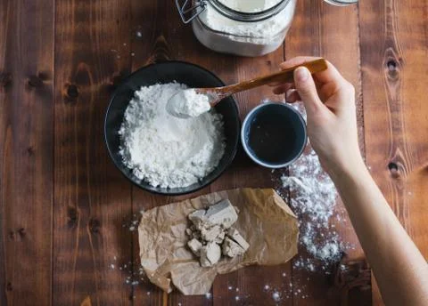 A woman's hand adding flour to make sourdough. Bakery concept. Stock Photos