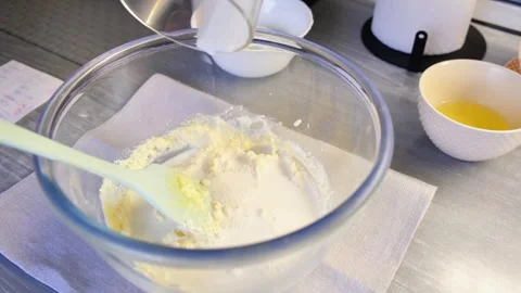 A woman's hand adding milk to pancake mixture in a glass bowl.  Stock Footage 304433015