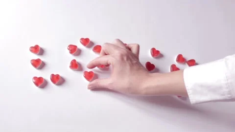Woman's hand adds the missing element to the word love. Jelly candies in hearts Stock Footage 231370271