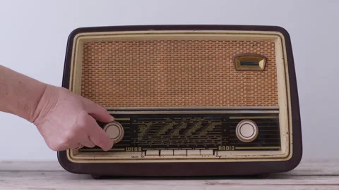 Woman's hand adjusting knobs on a vintage radio in a homely setting 動画素材 274653576