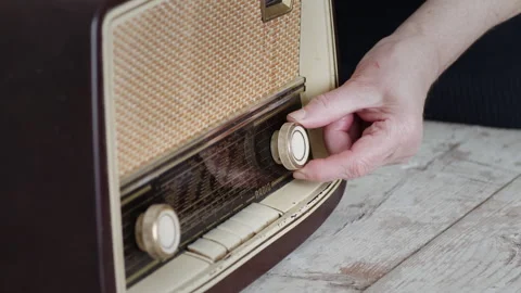 Woman's hand adjusting knobs on a vintage radio in a homely setting 動画素材 274655762