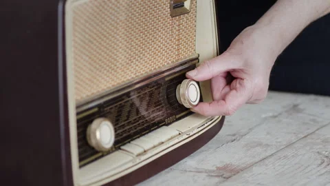 Woman's hand adjusting knobs on a vintage radio in a homely setting Video stock 274659058