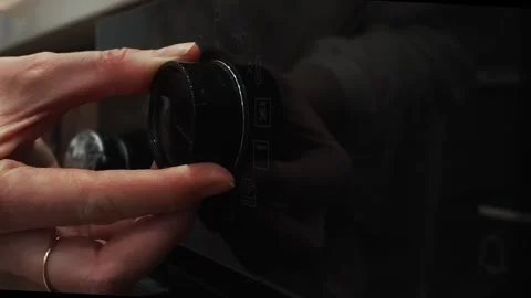 A woman's hand adjusting the oven Stock Footage 307383895